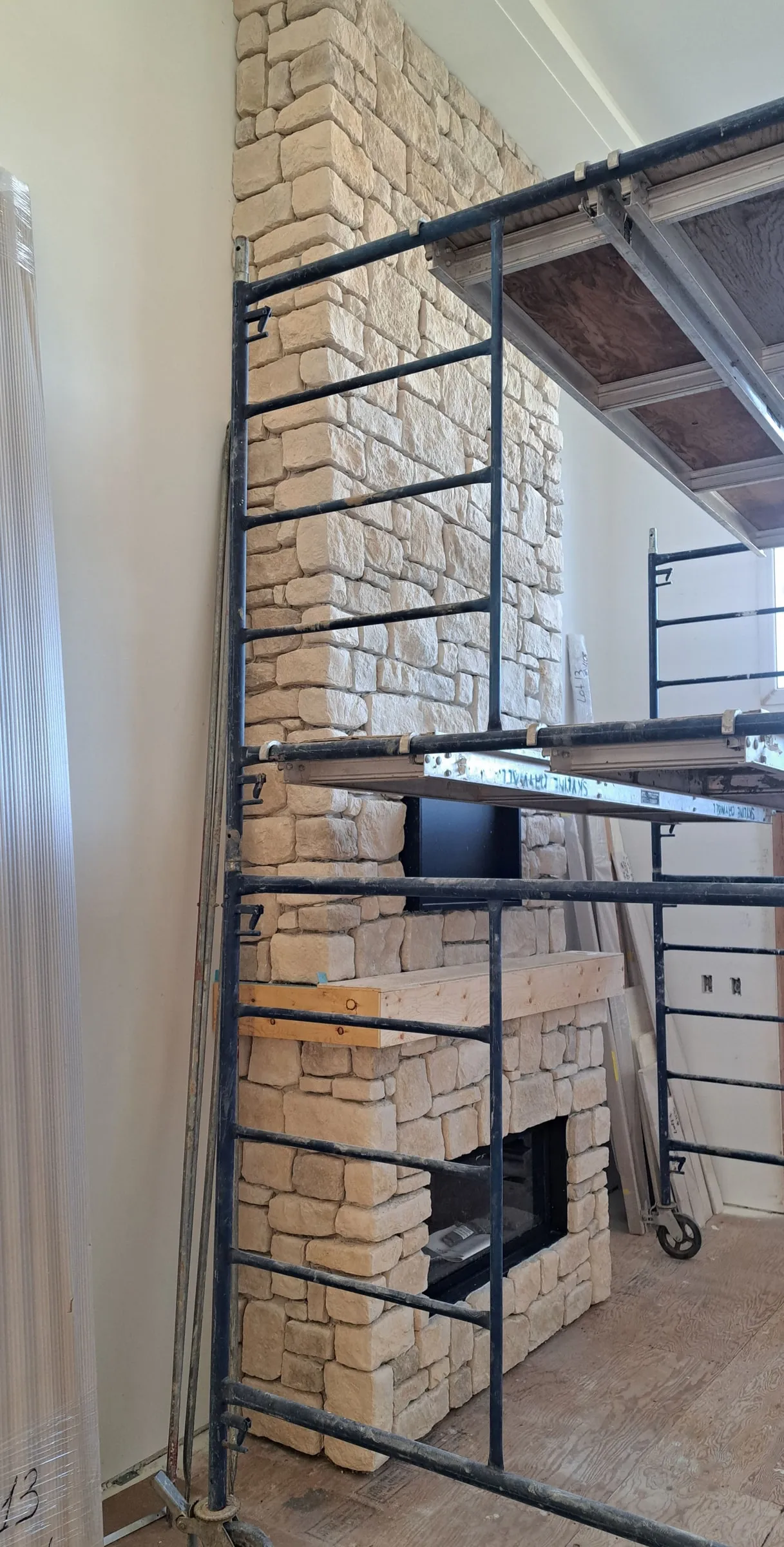 Floor-to-ceiling stone fireplace being built from scaffolding