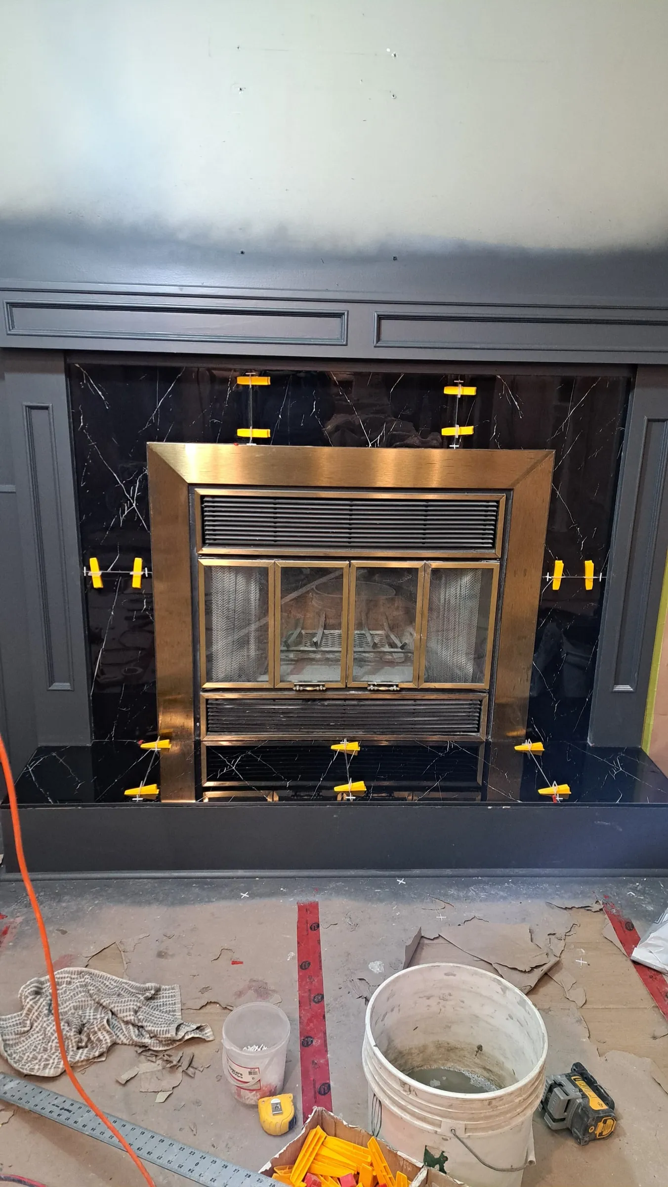 Black marble fireplace surround with levelling clips still in place around a brass firebox