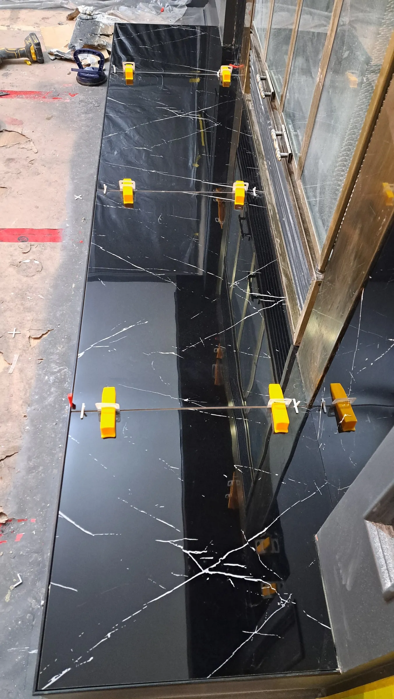 Close-up of a black marble panel held by levelling clips along the joint