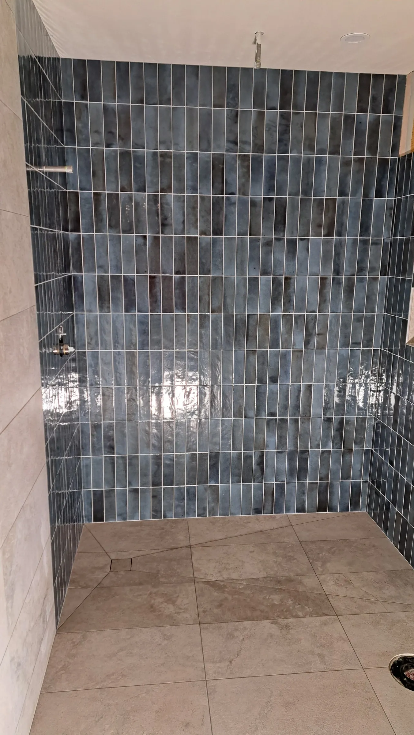 Finished shower in blue-grey stacked tile with large-format floor tile