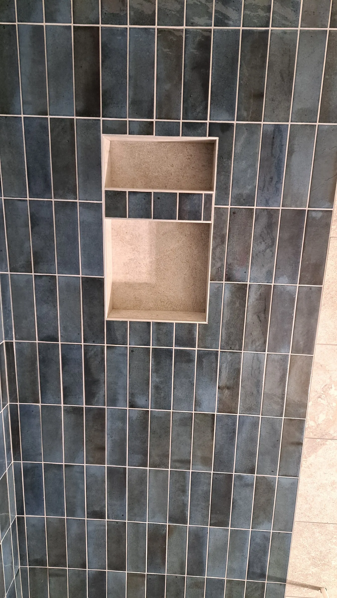 Shower wall in vertical stacked tile with a recessed niche framed and cut in