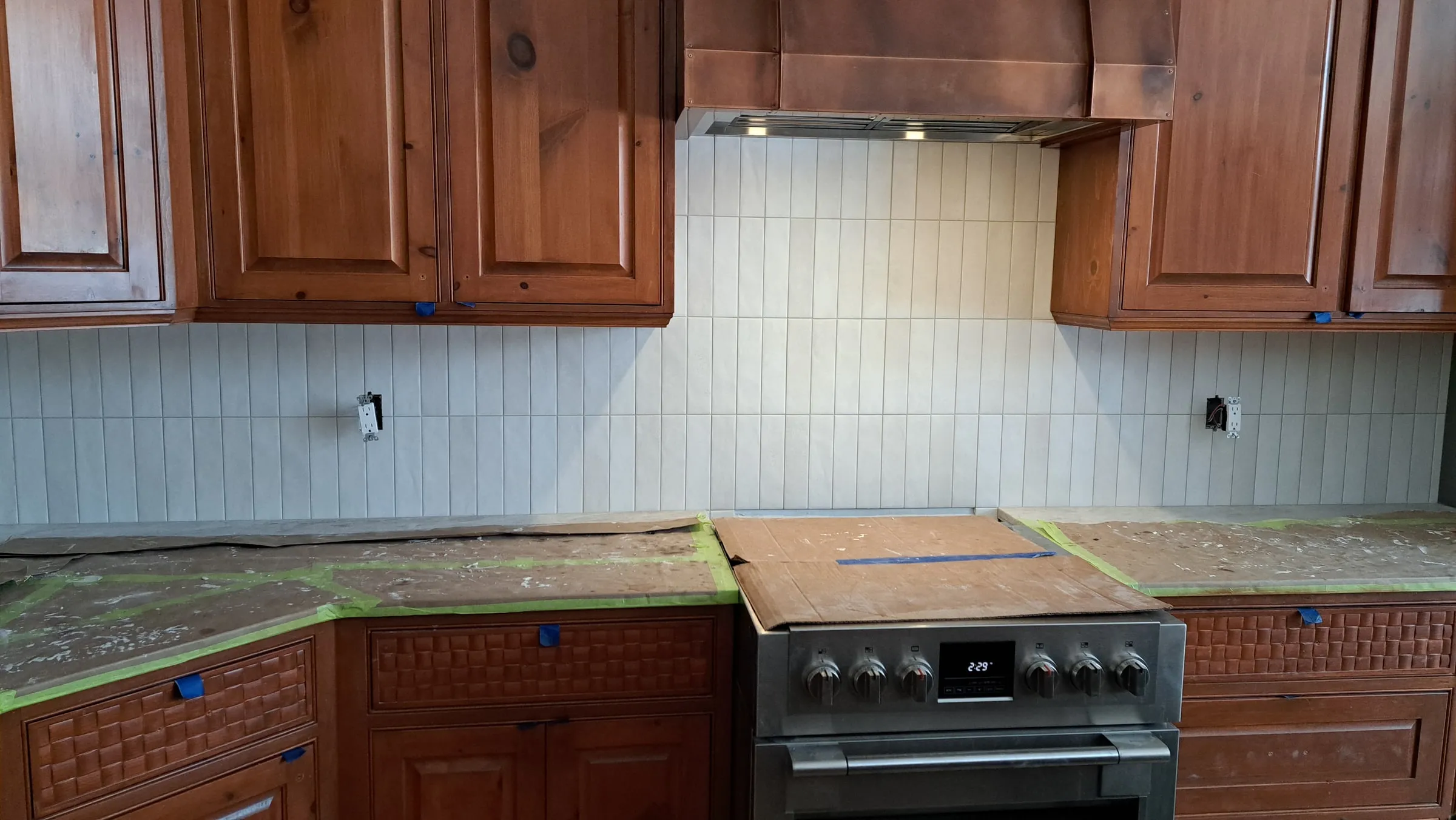 Kitchen backsplash going up in vertical tile with the countertop masked off