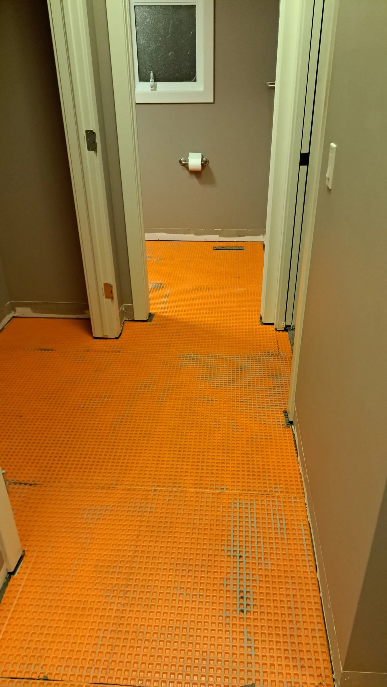 Orange uncoupling membrane covering a hallway floor before tile goes down