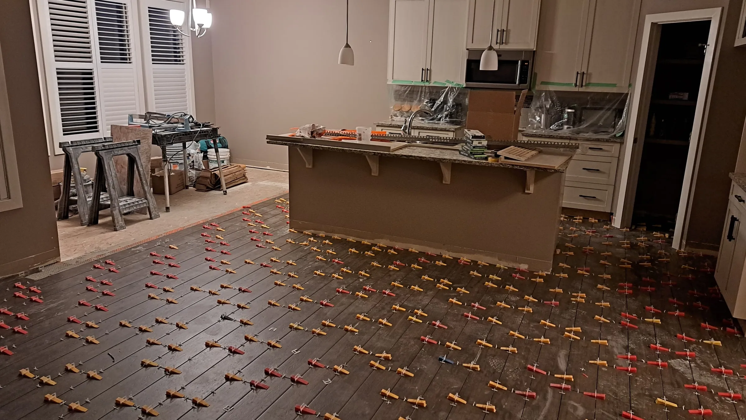 Kitchen floor tile being set with levelling clips and wedges across the room